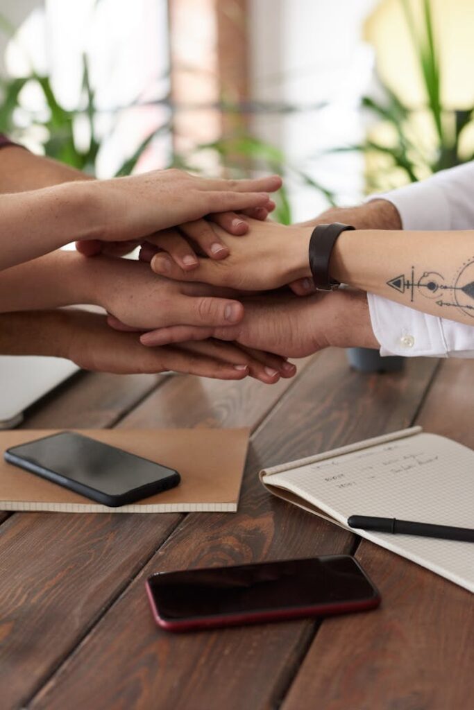 Mastering the First Impression: Your intriguing post title goes here Hands from a diverse team stack on a table symbolizing unity and teamwork in a modern office setting.